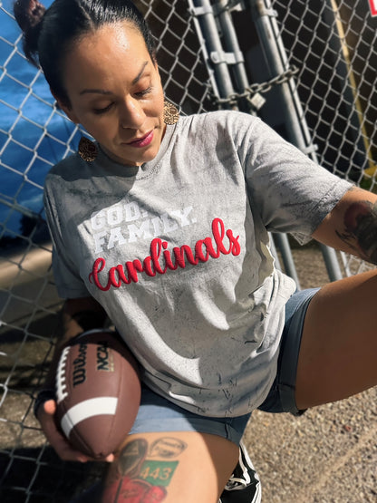 Woman wearing a 'Cardinals' shirt holding a football, standing in front of a chain-link fence.